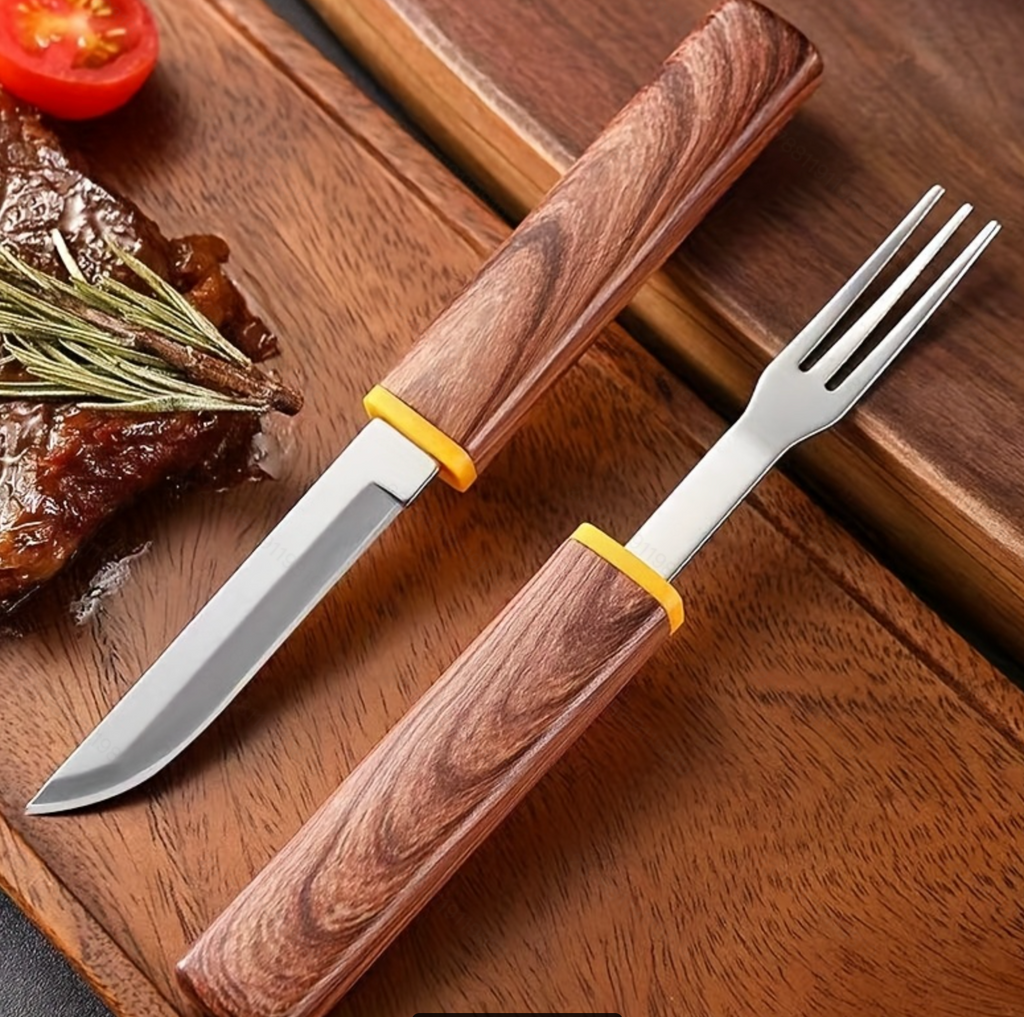 Interlocking fork and knife set on cutting board with steak and tomato